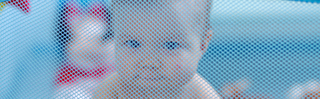 portable travel cot - toddler behind mesh wall